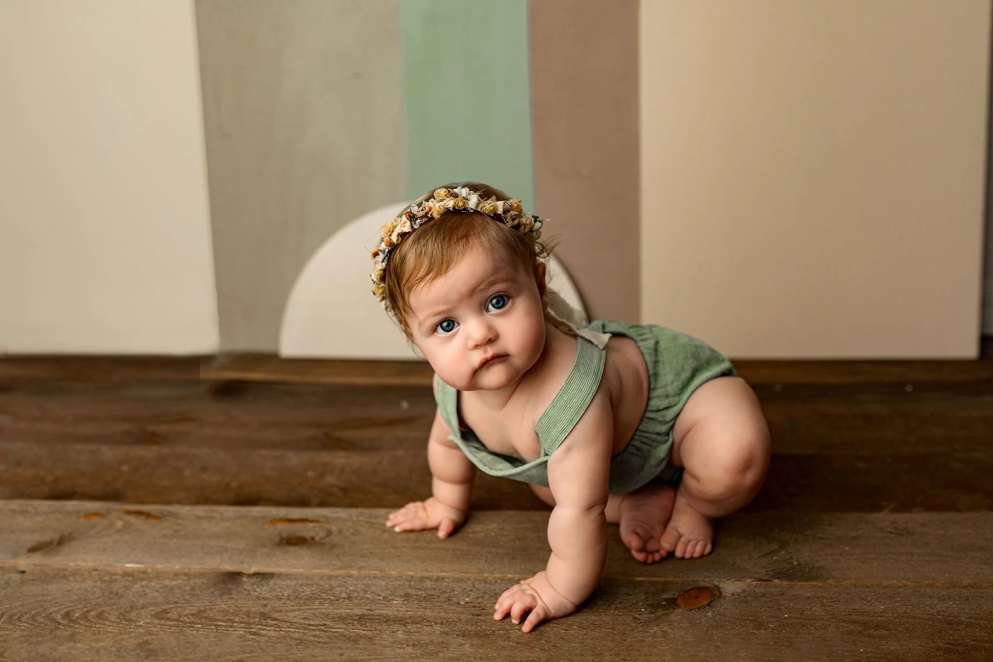 Organic colors and earth tones for one year old cake smash session located in Ponte Vedra, FL with baby girl wearing sage green and a flower crown in private luxury photo studio