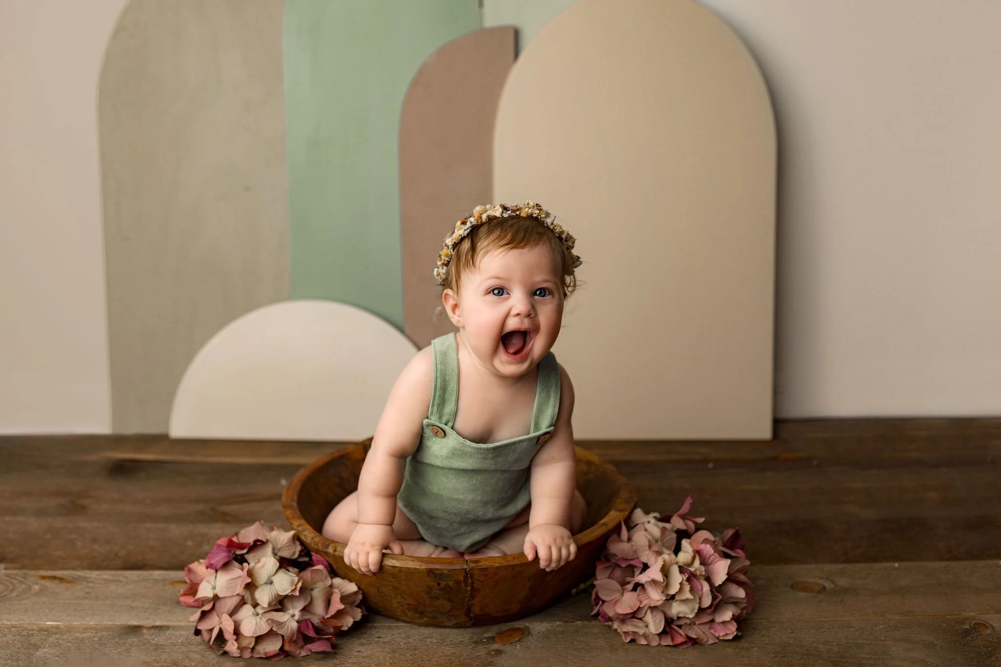 Cake smash pictures done with luxury family photographer in St. Augustine, FL with little girl in earth tone clothes and wooden bowl and floor and capturing milestone pictures