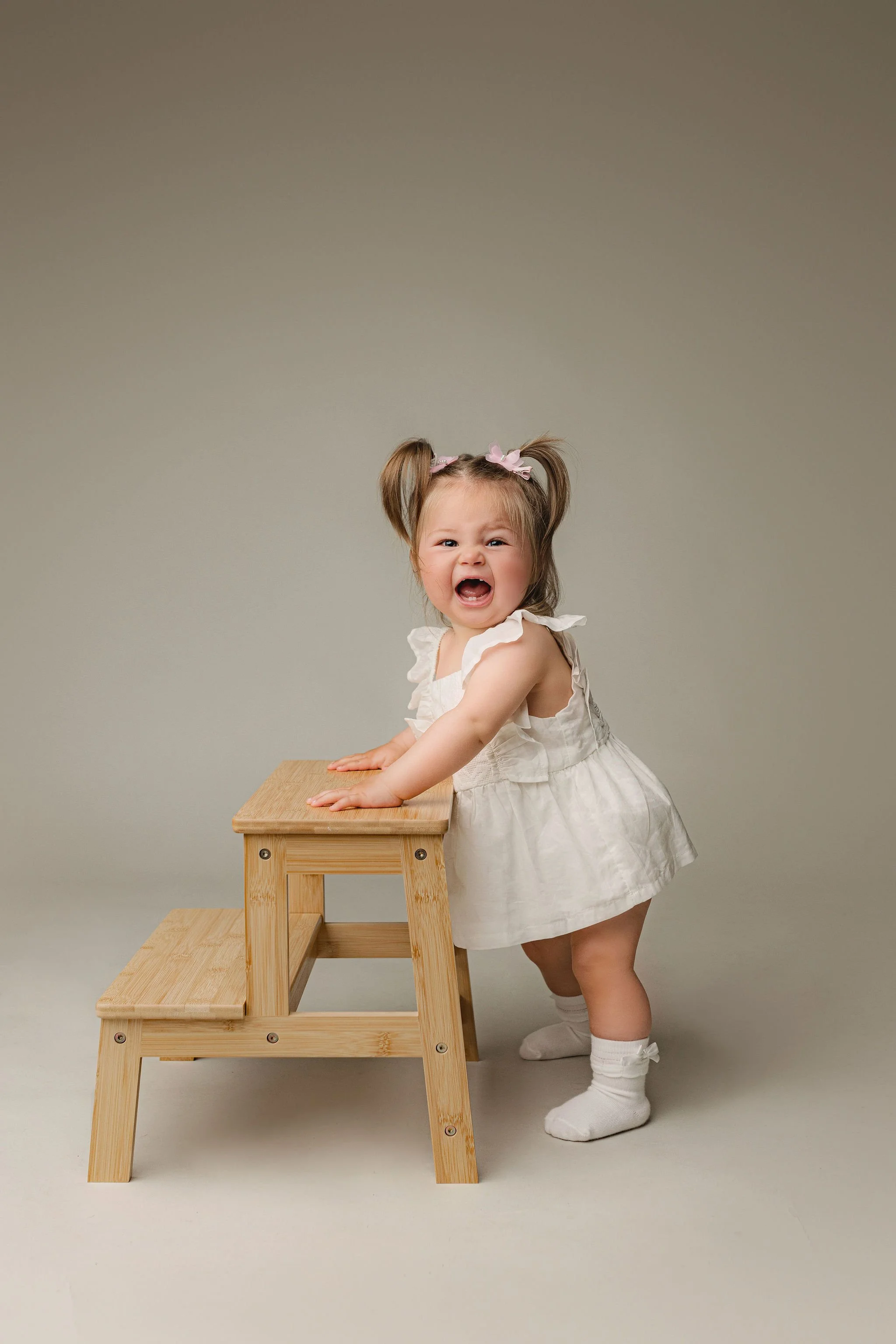 Milestone photo shoot at St. Augustine, FL studio with best family photographer in 32080, one year old girl with white dress on neutral background and minimal props