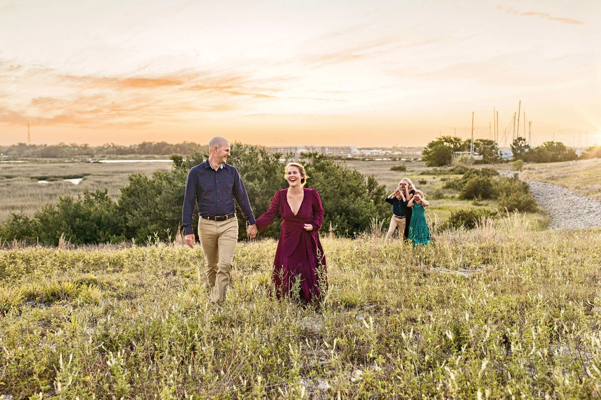 Jacksonville family photographer with couple and their kids in nature at sunset with jewel color clothing and long grass doing blended family photo session