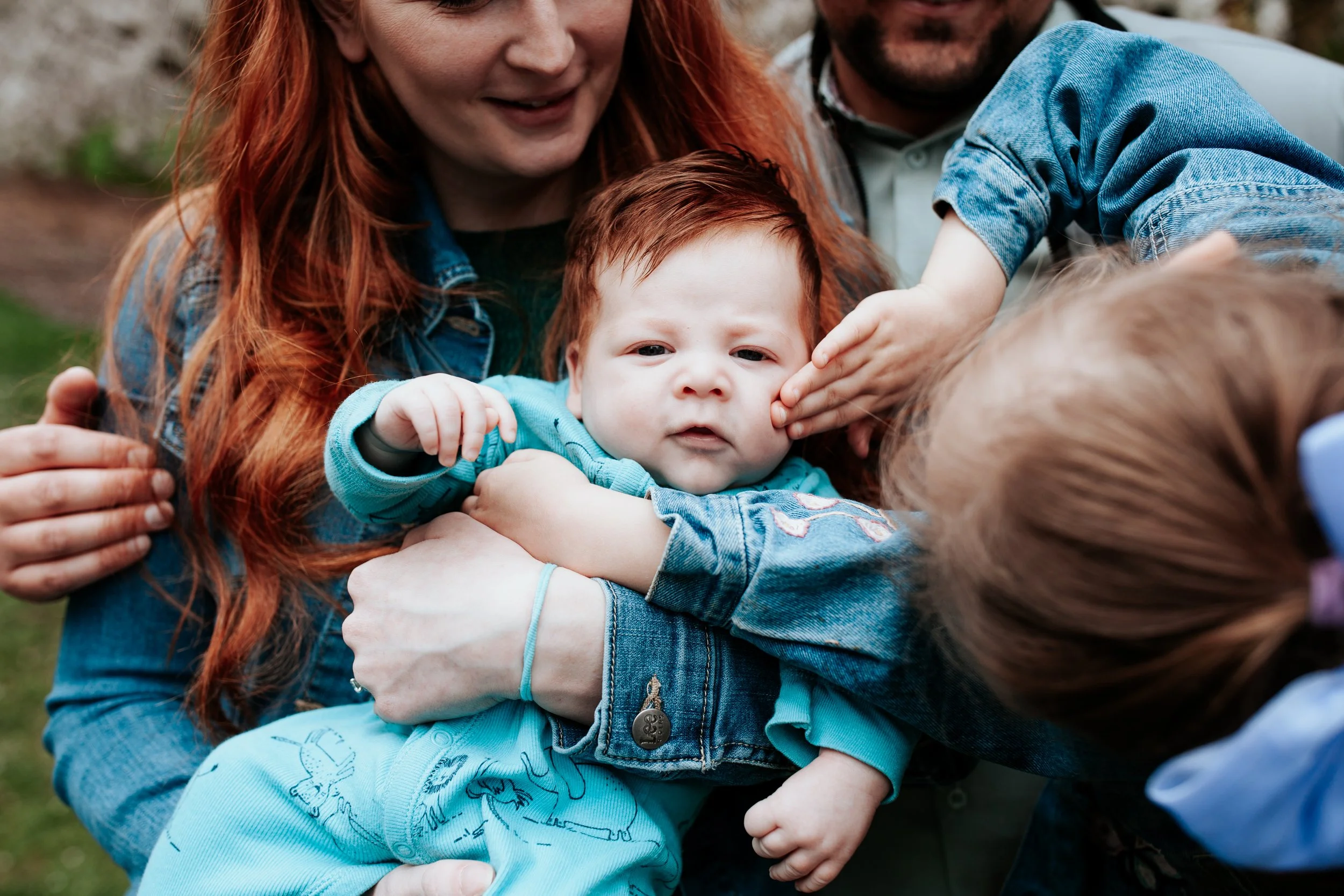 a girl plays with her baby brother under a cherry blossom in seattle