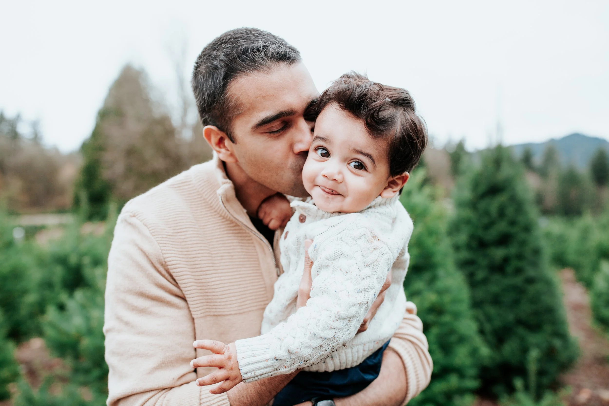a dad hugs his son at the tree farm for holiday mini sessions