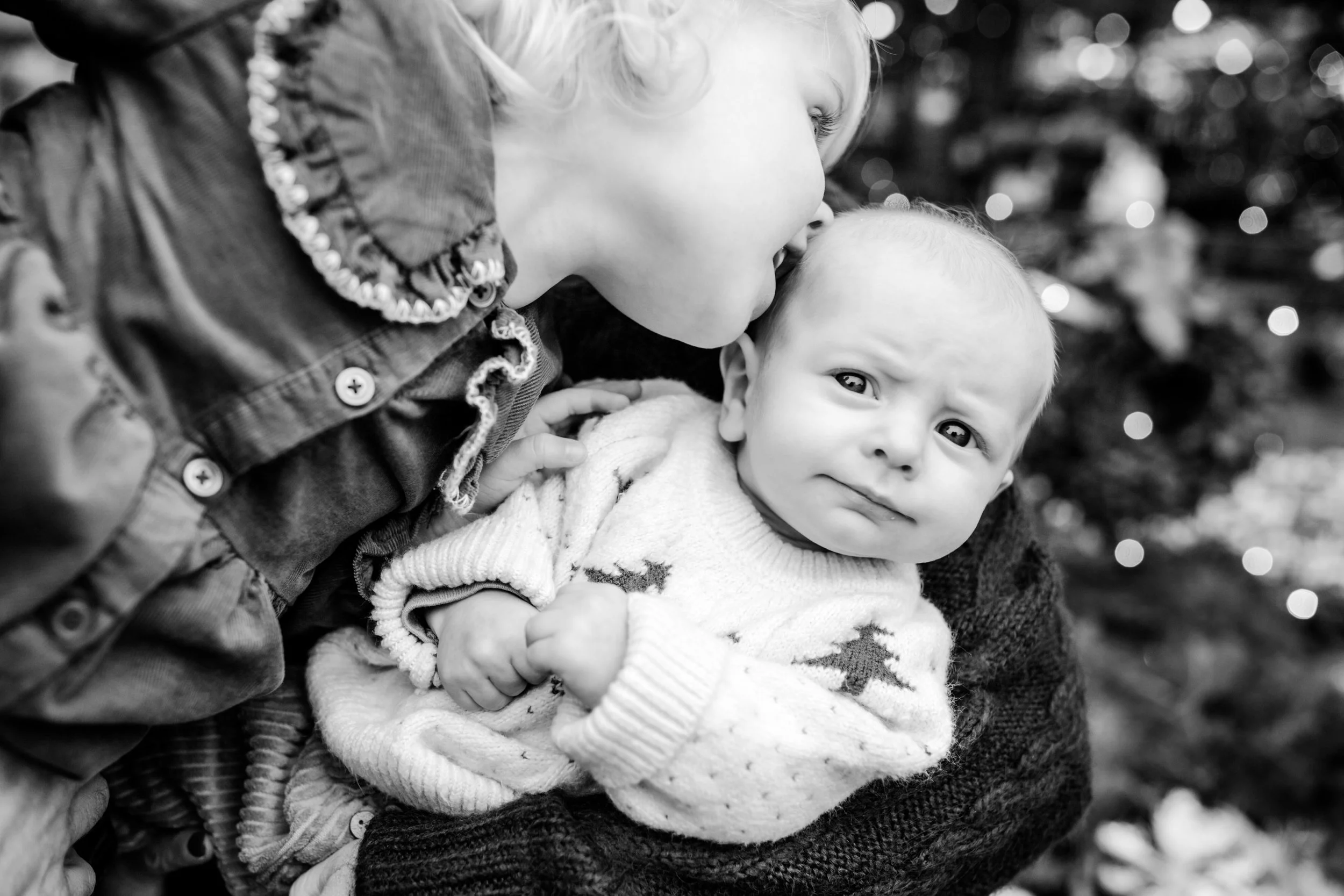 a girl kisses her baby brother for holiday photos