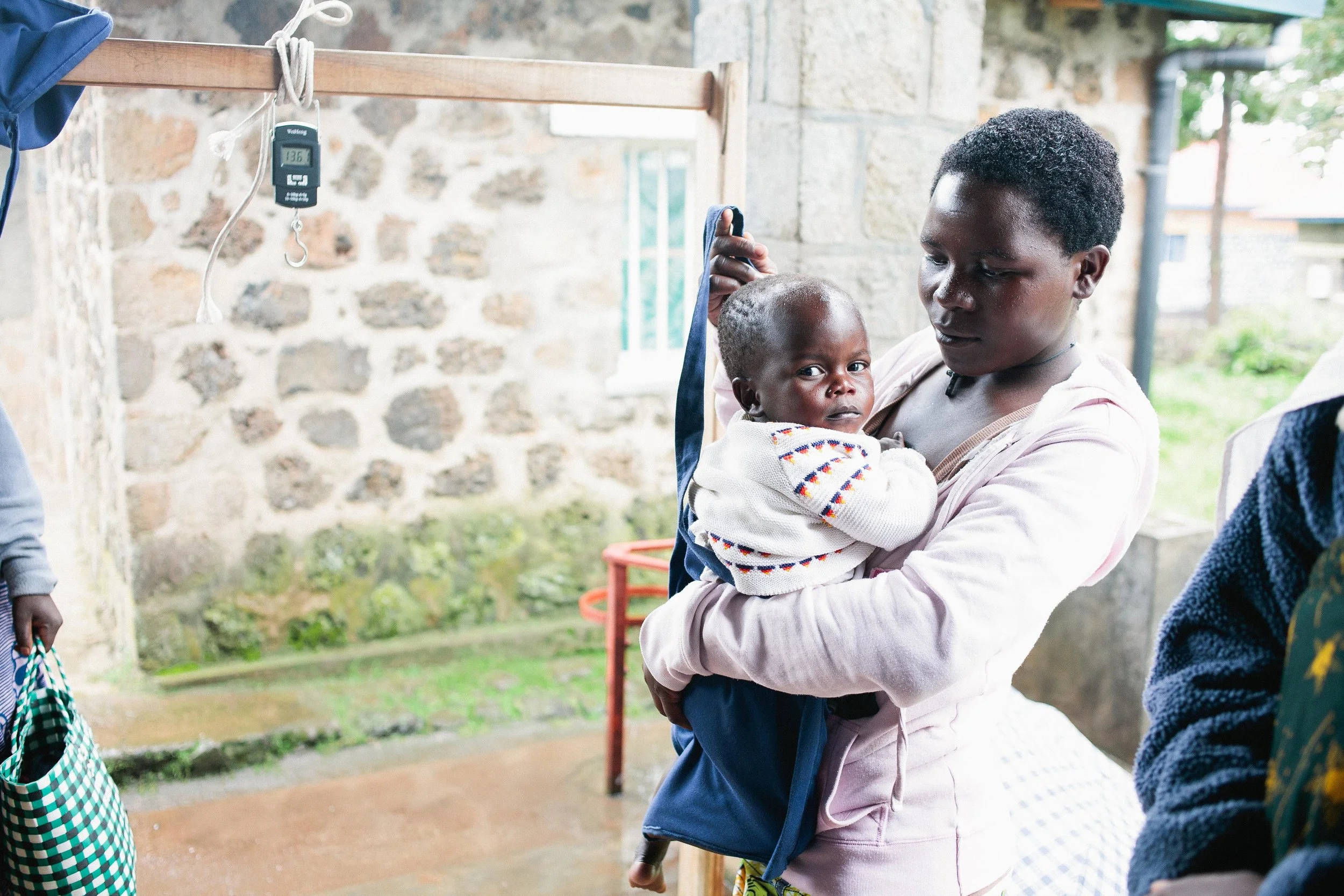 A caregiver helps weigh her child