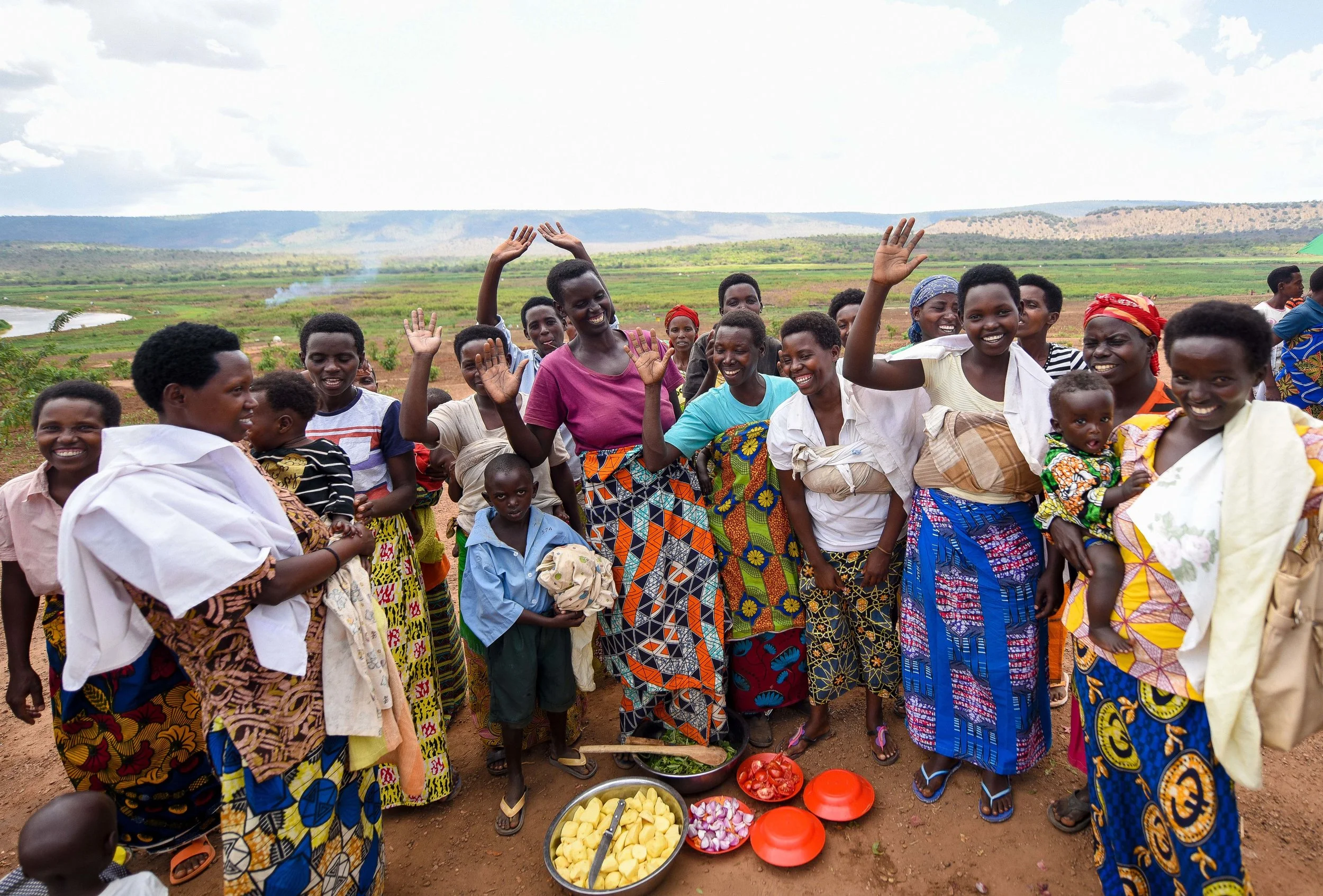 Burundian women enrolled in GHI's health and agriculture trainings at Mahama Refugee Camp wave to the camera during a cooking demonstration on October 6, 2017.