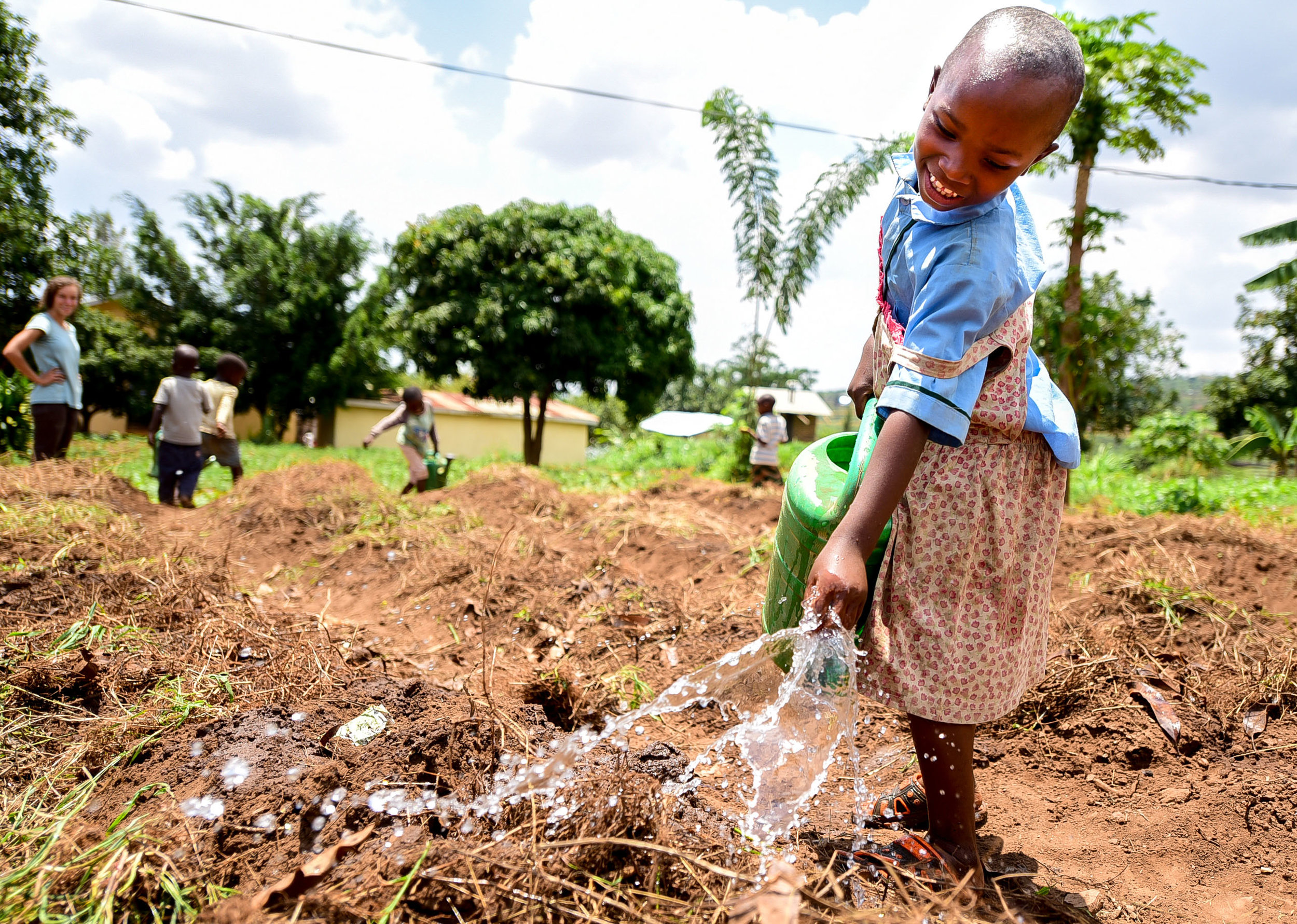 Iradukunda Florance, a member of GHI's Early Childhood Development program, helps water crops.
