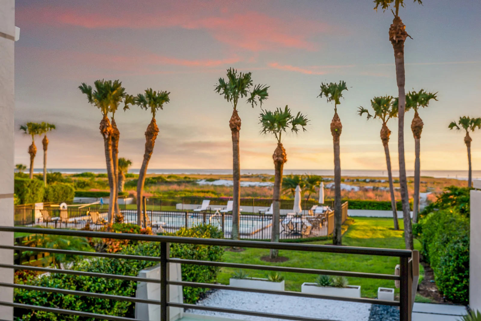 The view from the back of this modern Sarasota School of Architecture townhome is that of towering palms, swaying grasses, and a path straight to your own slice of Siesta Key Beach.