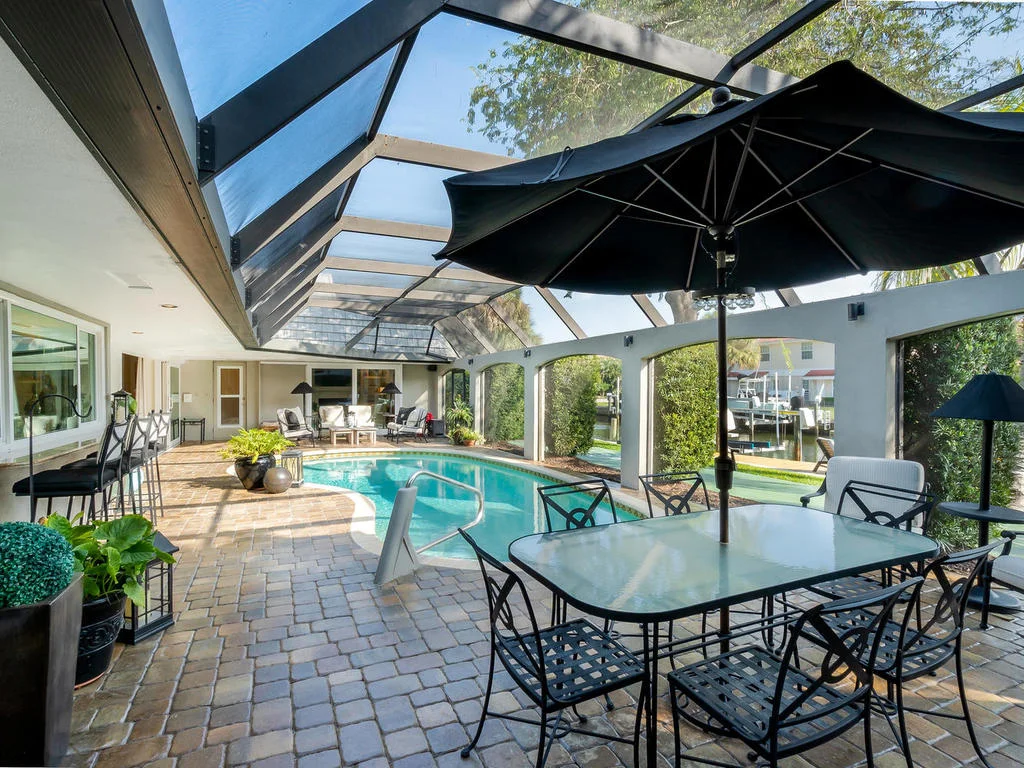 The serene scene on the lanai includes room for entertaining, bar seating, and the sparkling waterfront pool.