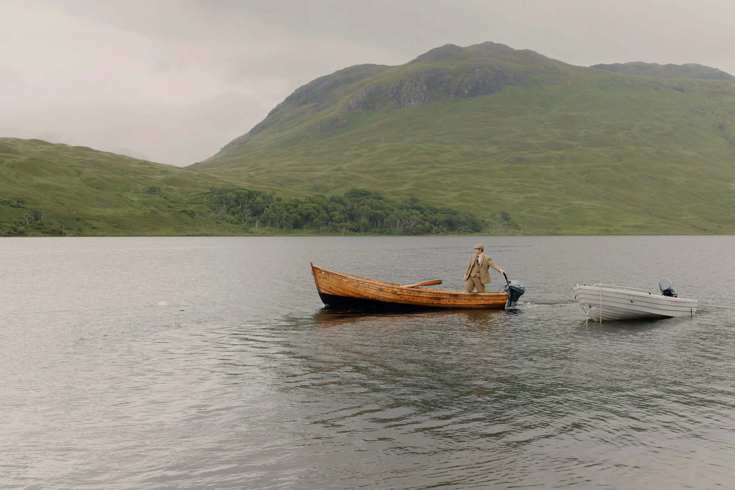 Ghillie on a wooden boat on a loch in the scottish highlands