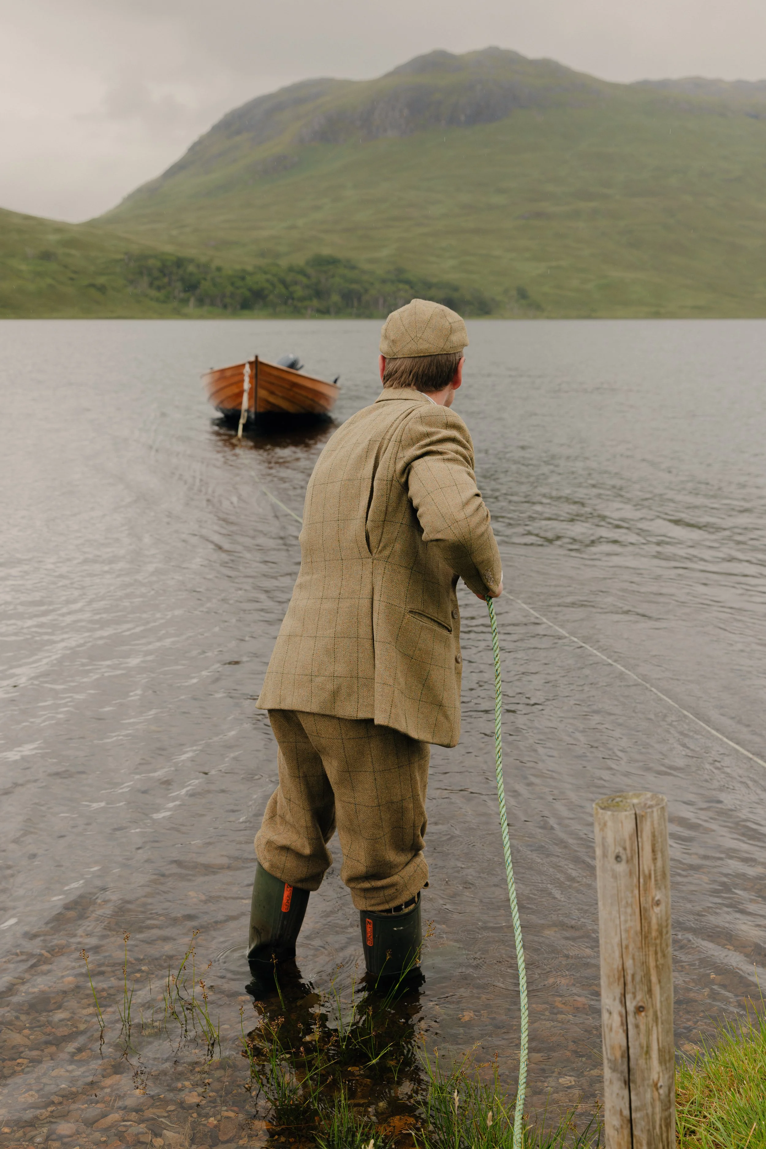 Moddy Highlands commercial photography featuring a wooden rowing boat on a loch with mountain backdrop, styled for a Scottish Estate