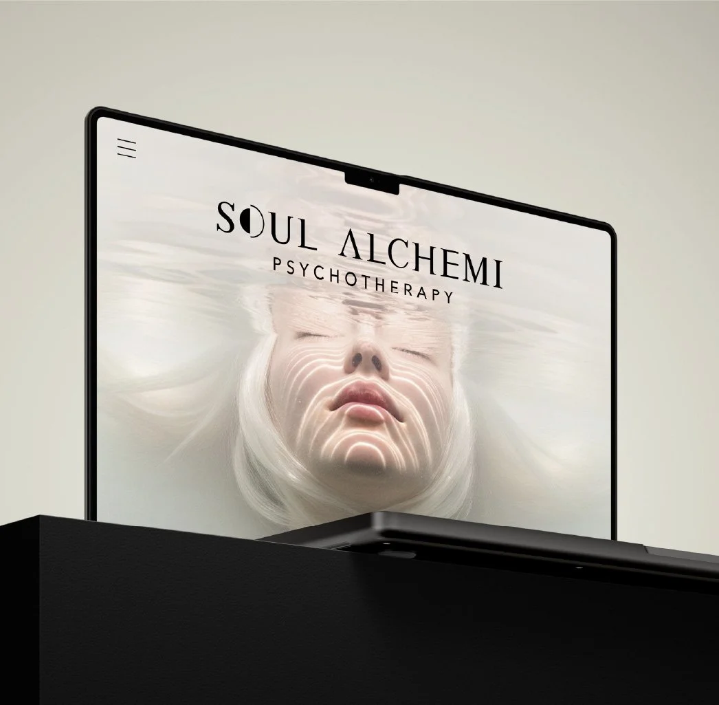 A computer monitor displaying the words "Soul Alchemi Psychotherapy".
