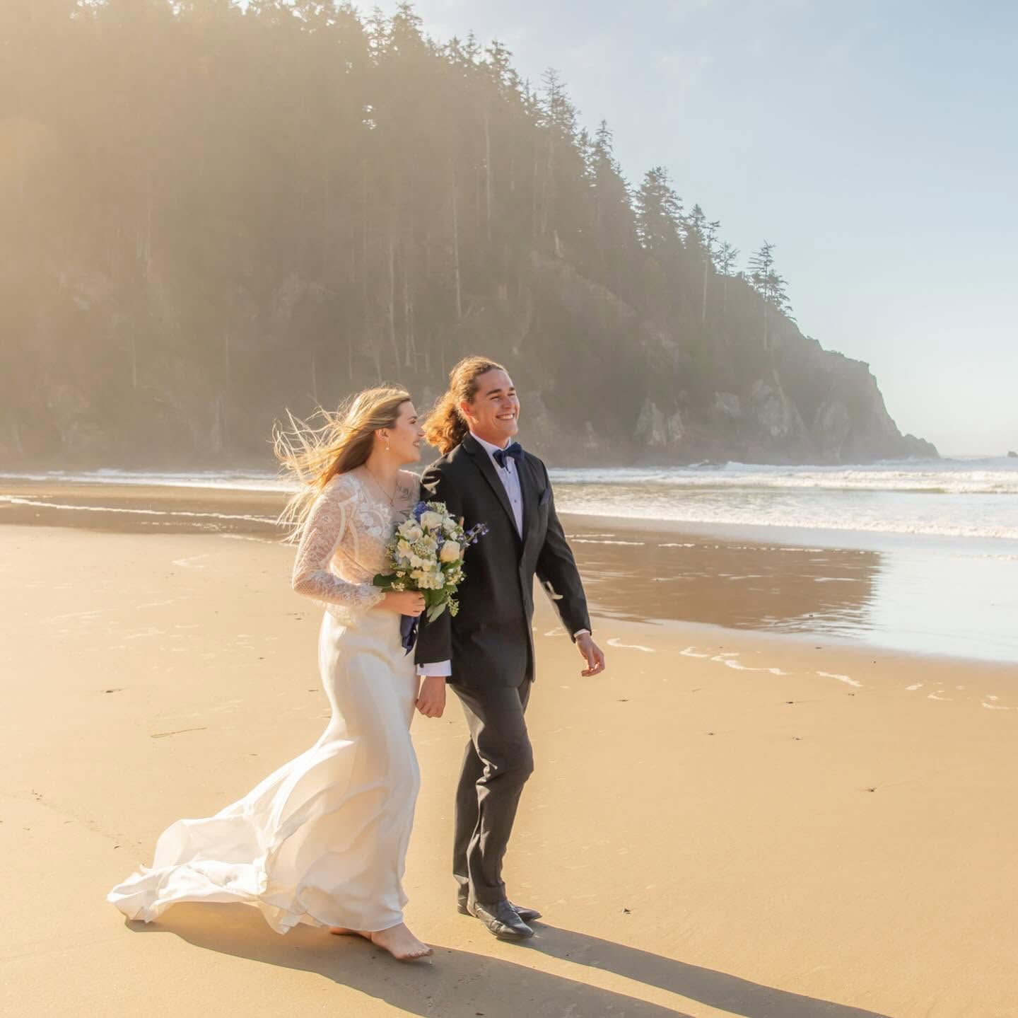 Couple walking along Cannon Beach with Haystack Rock in the background