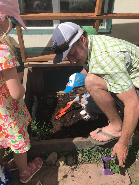 A parent helps the Mountain Sprouts students prepare and plant the garden for spring!