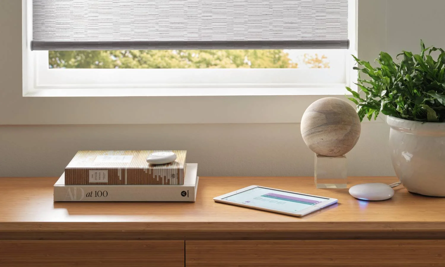 Hunter Douglas PowerView® Automation remote, app on a tablet, and Gateway system near motorized roller shades