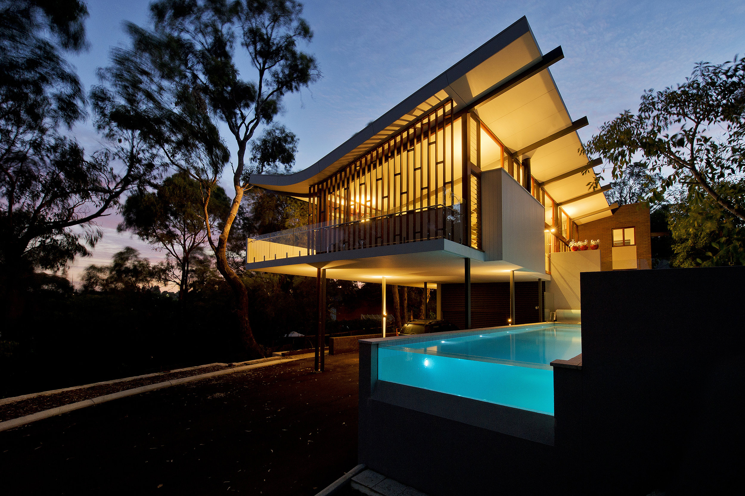 Mayfair St. The living and play areas sit high in the canopy of tall established trees, the design draws inspiration from this canopies of foliage. The gentle sweeping roof form creates a draped canopy to the living spaces and opens the space up to both the Northern light and the Southern views. An architectural solution was engaged that allowed the frame of the structure to be expressed to allow the beauty of the structural solution to be enjoyed. This connects the ‘trunks’ of the lower columns with the ‘branches’ of this upper canopy, strengthening this theme. This sculptural loft space floats above the entry and leads you to the massive and grounded masonry form. This brick element houses the private quiet spaces, while the free-form lightweight glazed living spaces are open and liberally penetrated. The interface between these two forms acts as the circulation and entry spaces. The living space enjoys sweeping views across the Claremont valley and framed views through tree and a timber screen to the city’s skyline in the distance. The importance of these views permeate the design such that framed views are enjoyed from all bedrooms, living spaces, the kitchen and the Southern external living spaces. Sun in and out to the South to emphasise the views.