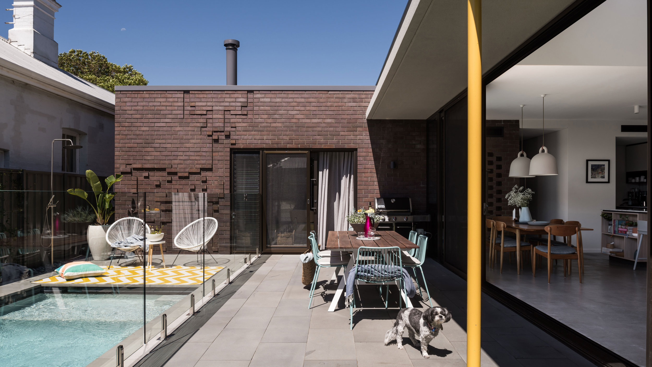 Northwood Rd. This residence explores the idea of possibilities of efficient use of space within framework of passive solar principles and parameters of local council regulations. The home sits on a 336m² block running East West for a young couple, accommodating their immediate lifestyle needs and now as a family. Open plan living areas are connected to the outside and even an intimate retreat. The buildings contribution to the street is modest with the combination of raw textures from the face brick, white rendered wall and the warm tones of the cedar cladding. The site is in a character protection area, so the interpretation of ‘pitch roof’ requirement was achieved by sculpting a strong double storey pitched roof form running the length of the south boundary. Attached to the north side of the pitched roof form is the single storey box. This delineates the pool courtyard and carport to the East.