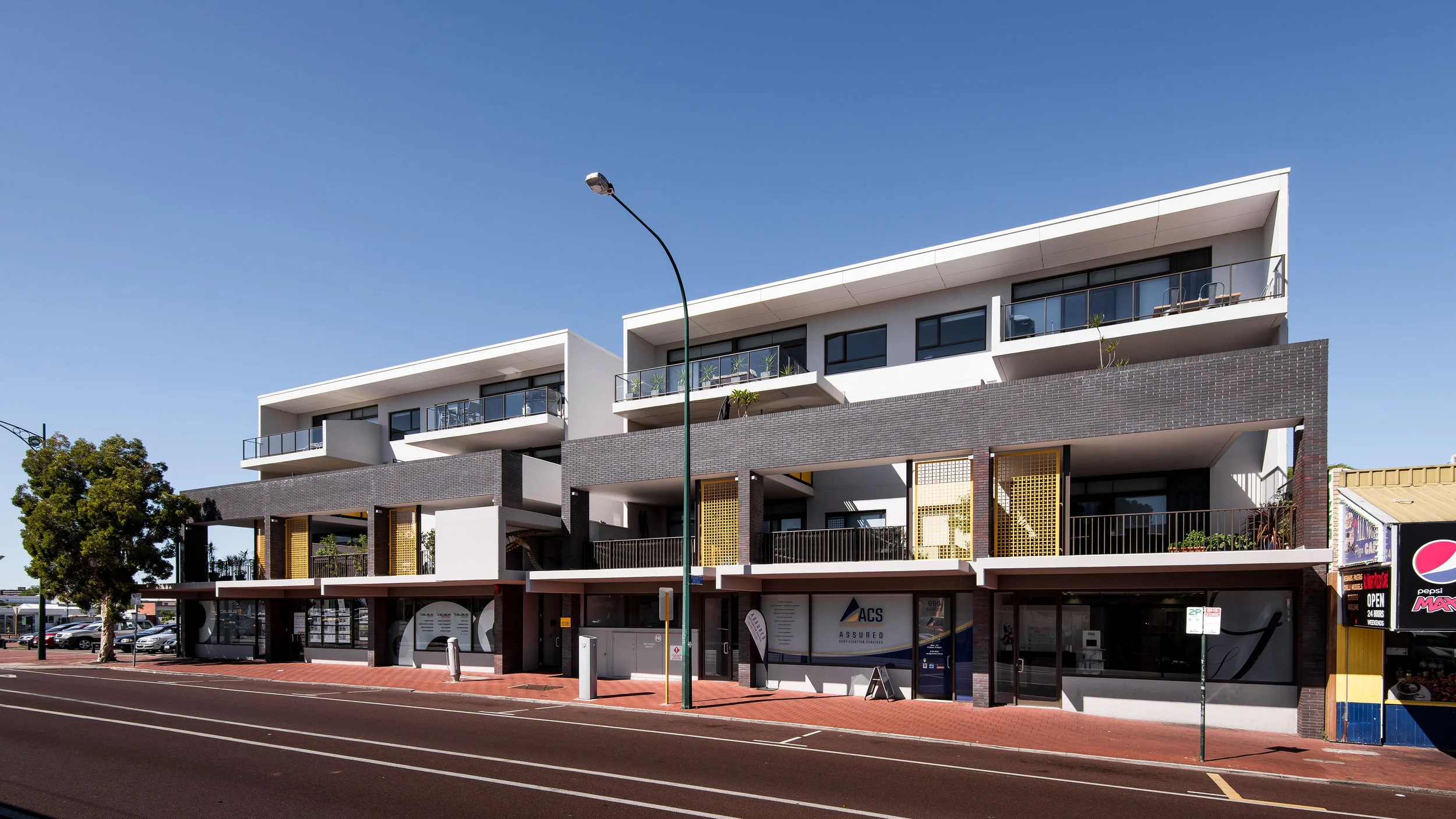 Albany Hwy. 1. The rapid and poorly considered infill developments on Albany highway was the key design consideration for this project. We worked closely with the council to develop frameworks for the future infill developments on Albany highway and this project became the council’s exemplar for future development. We also focused on creating a building that addressed and reinforced the streetscape and the shop front scale. 2. A significant piece of urban artwork was integrated into the building design. A projecting frame was created for this sculptural work. The artist and architects worked collaboratively to develop a response that articulated context while referencing the building. The entrance lobby was designed to be integrated into a café to activate this space during the day. The design includes generous first floor balconies which was important for these balconies to enliven the street. 3. The building form took the rhythm of the commercial shop front context that is left in patchwork on the Albany highway street frontage. A colonnade references the scale of this context and individual canopies attached to each bay further emphasises this human scale. 4. The project achieved concessions on plot ratio and height that significantly exceeded peer developments. These were achieved through a collaborative DAC process in which the advantages of a smaller footprint, taller builder were articulated and accepted. 5. The project team all brought innovation and experience to the project. The work of the artist and the samples and interaction we had was particularly rewarding and successful. 6. The project provides apartments to the entry level of buyers. The materials and finishes celebrate this honesty through simplicity and modest usage. 7. The orientation of Albany highway made a simple orientation solution difficult. We provided generous outdoor spaces and protected northern openings. The development includes predominantly corner planned apartments which allow simple cross ventilation. 8. The client had developed two projects before our engagement which ignored good planning framework resulting in flawed planning outcomes. This, our first collaboration, delighted the client and led to 7 subsequent projects each building on the former. PROJECT SUMMARY 696 Albany highway is an exemplar development for urban infill in East Victoria Park while responding to the re-existing shopfront context, now much denuded. The building form took the rhythm of the commercial shop front context that is left in patchwork on the Albany highway street frontage. A colonnade references the scale of this context and individual canopies attached to each bay further emphasises this human scale. The rear of the building focussed on passive surveillance of the rear lanes while enjoying the excellent Northern light. Central corridors are internalised, but also naturally ventilated, to create a higher quality urban environment for the tenants, without sacrificing access to cross-ventilation. A significant piece of urban artwork was integrated into the building design. A projecting frame was created for this sculptural work. The artist and architects worked collaboratively to develop a response that articulated context while referencing the building. The building, finished in the nascent years of the apartment boom and has become a strong exemplar of elegant simple planning and strong urban and community engagement. SUSTAINABLE ARCHITECTURE CATEGORY The orientation of Albany highway made a simple orientation solution difficult. We provided generous outdoor spaces and protected northern openings. The development includes predominantly corner planned apartments which allow simple cross ventilation. The central apartments include projecting wind scoops which draw breezes through and split planning which makes internal cross ventilation simpler to achieve. The design includes cowled windows on the northern façade to provide privacy, but also protection from summer sun.