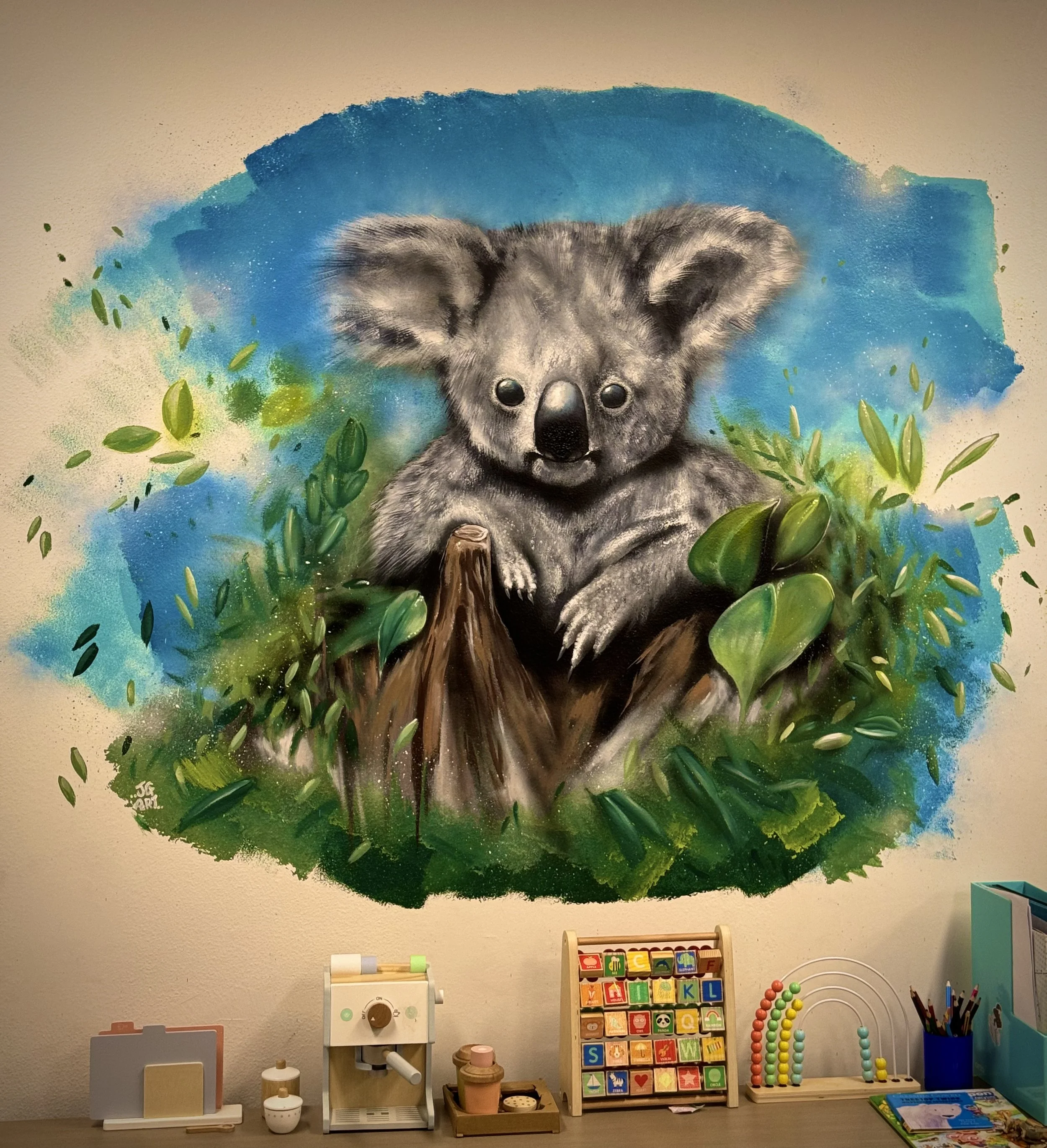 Koala Mural. Koala sitting on tree stump with leaves and blue sky. Located in Newcastle.