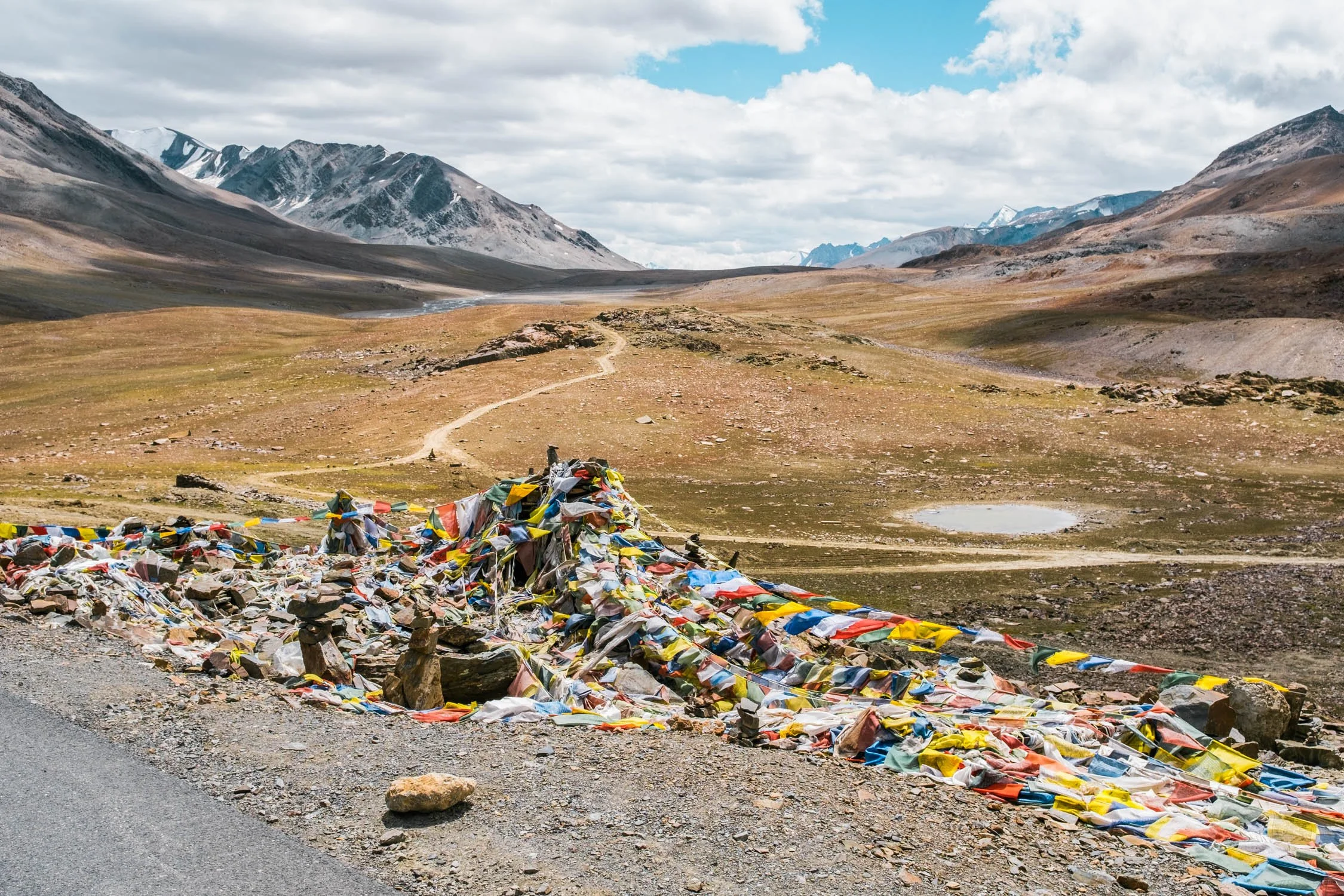 Berglandschaft mit Bergen im Hintergrund und bunten Gebetsfahnen im Vordergrund