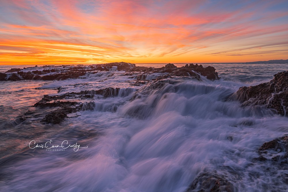 Long exposure ocean photography at sunset in Palos Verdes, California, showing turquoise water rushing over dark coastal rocks under a pink and blue sky.