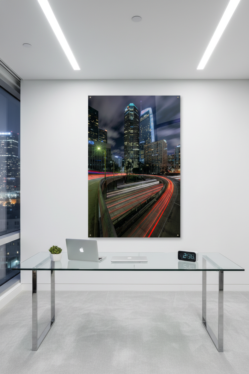 Large Downtown LA freeway light trails acrylic print mounted above a sleek glass desk in a high-rise office with city views.