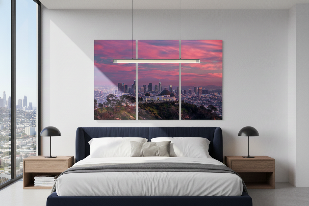 Three-panel triptych wall art of the Griffith Observatory and LA skyline hanging over a king-size bed in a modern apartment bedroom.
