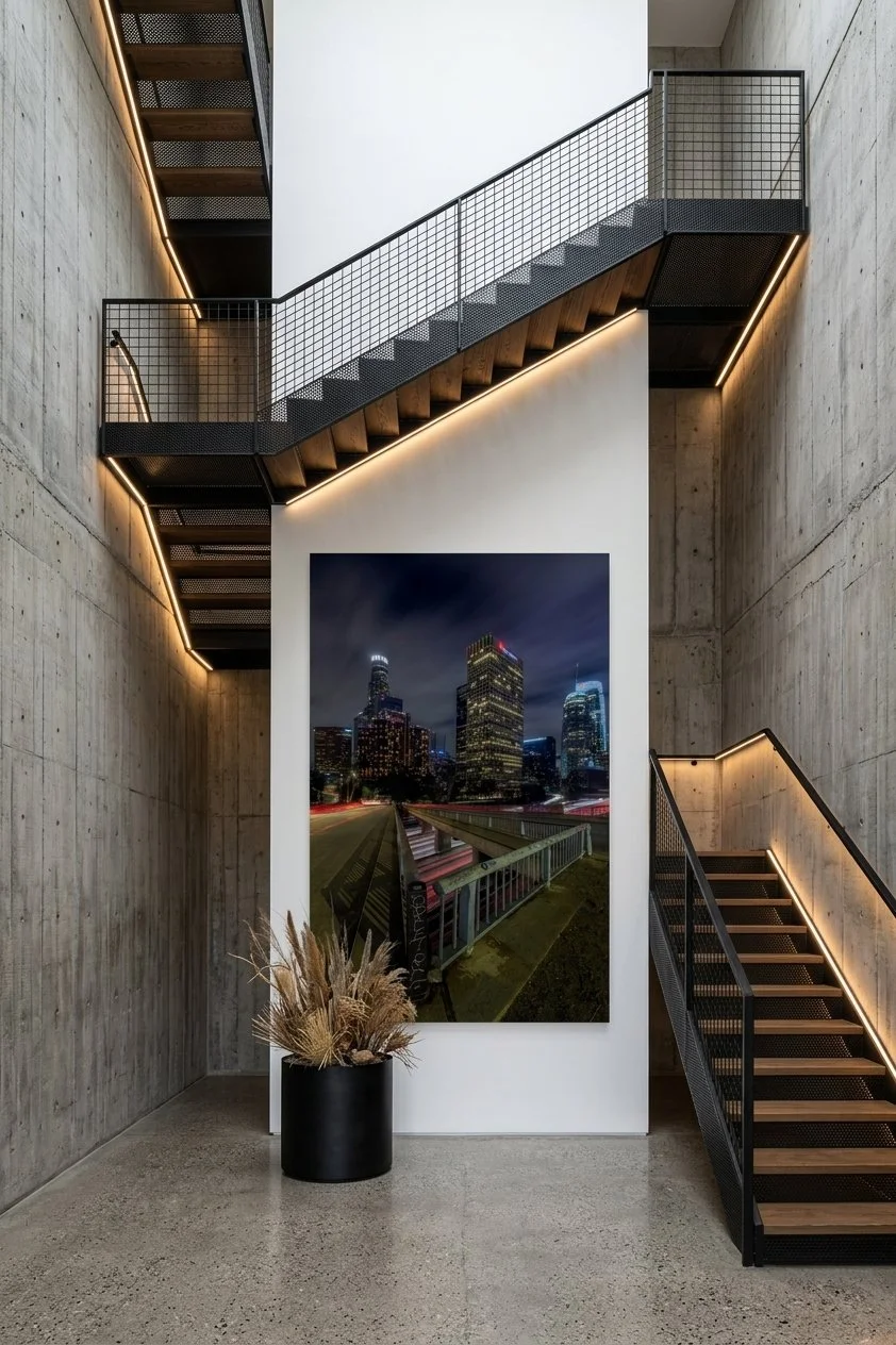 Over-sized vertical Downtown Los Angeles urban photo print displayed on a central wall surrounded by modern steel and wood staircases.