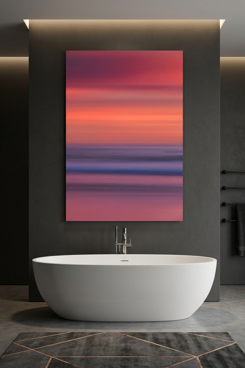 Vertical abstract coastal sunset wall art displayed on a dark gray plaster wall above a freestanding white soaking tub.
