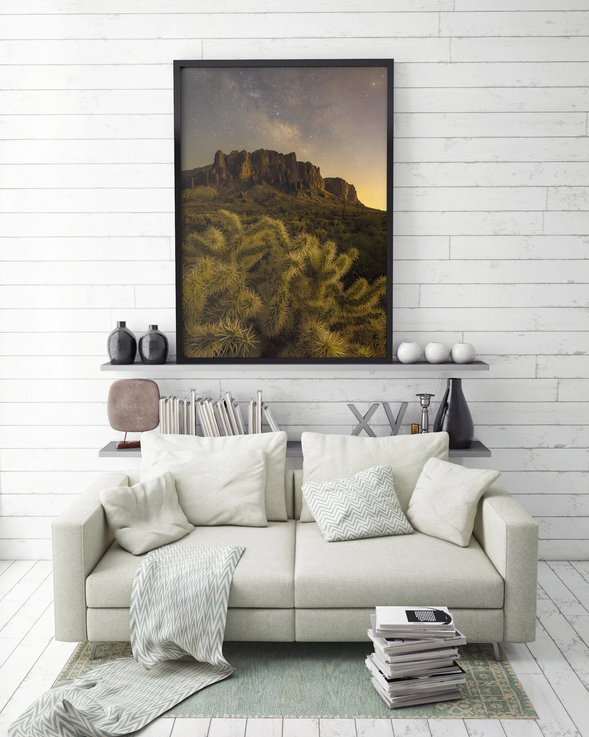 Framed Superstition Mountains Milky Way artwork sitting on a shelf above a cream sofa against a white shiplap wall.