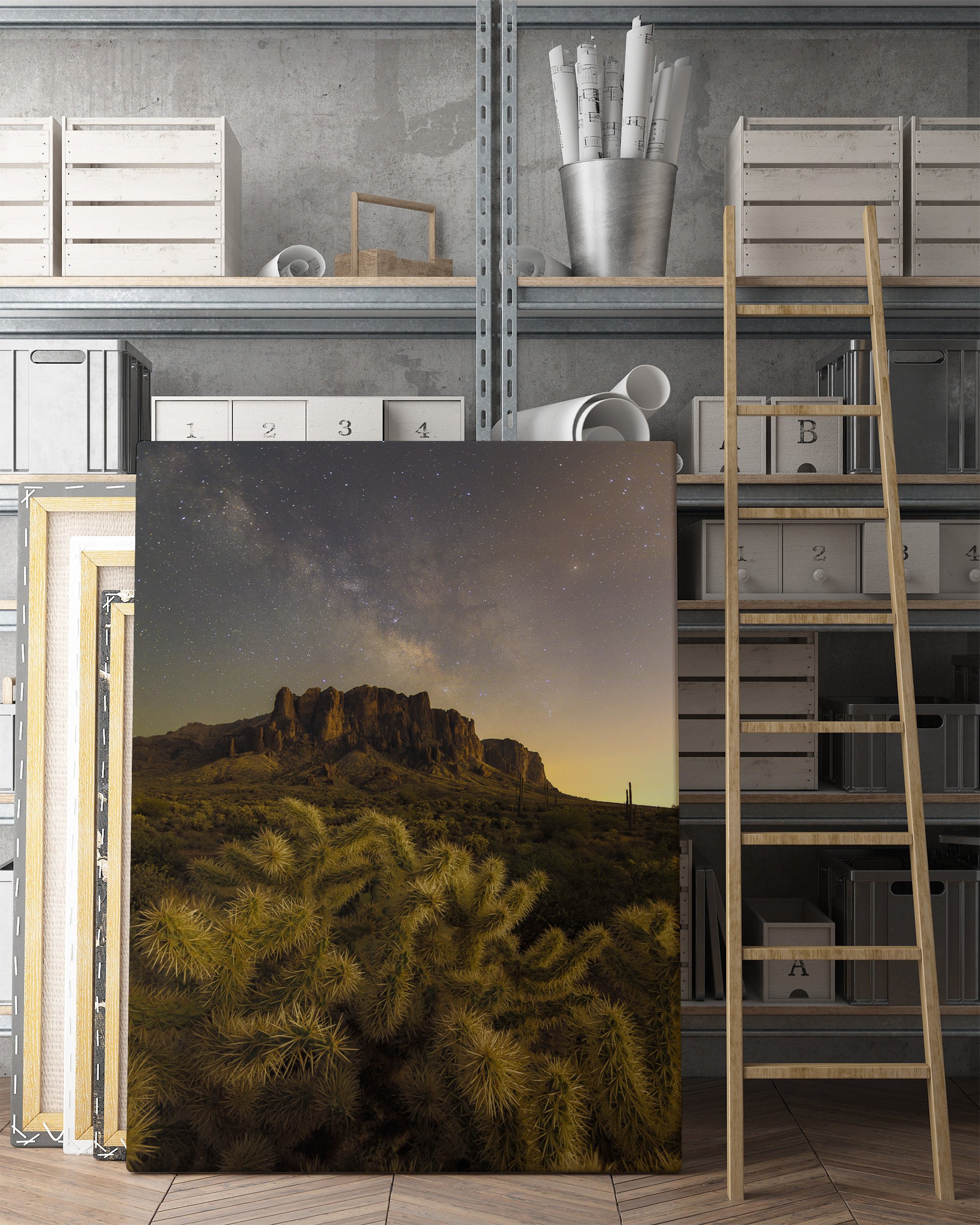 Unframed Superstition Mountains desert canvas resting on the floor of an industrial loft studio next to a wooden ladder.