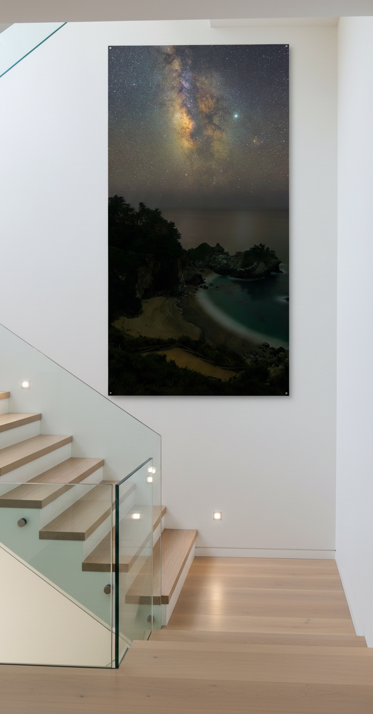 Oversized vertical Big Sur Milky Way acrylic print displayed on a tall white wall along a modern glass staircase.