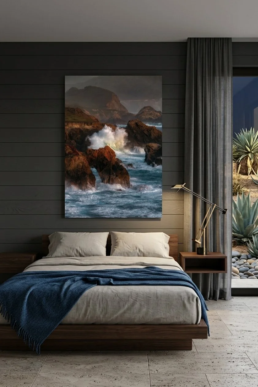 Large frameless Big Sur ocean print mounted above a dark wood platform bed with a navy blue blanket on a charcoal shiplap wall.