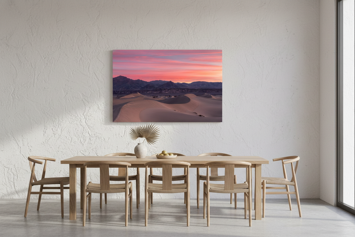 Horizontal Death Valley sand dunes art print hanging above a light oak dining table with six wooden chairs in a sunlit room.