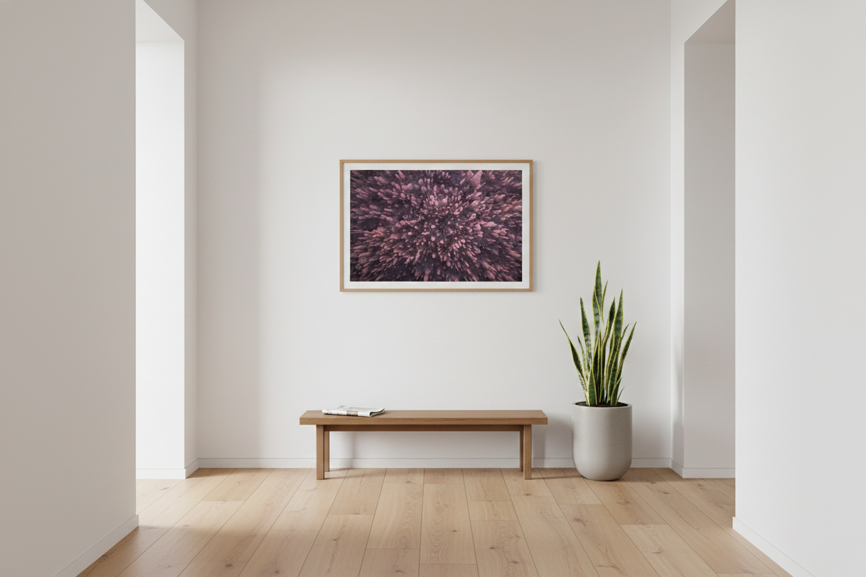 Framed horizontal Death Valley salt formation picture hanging in a spacious white hallway over a minimal wooden bench and potted plant.