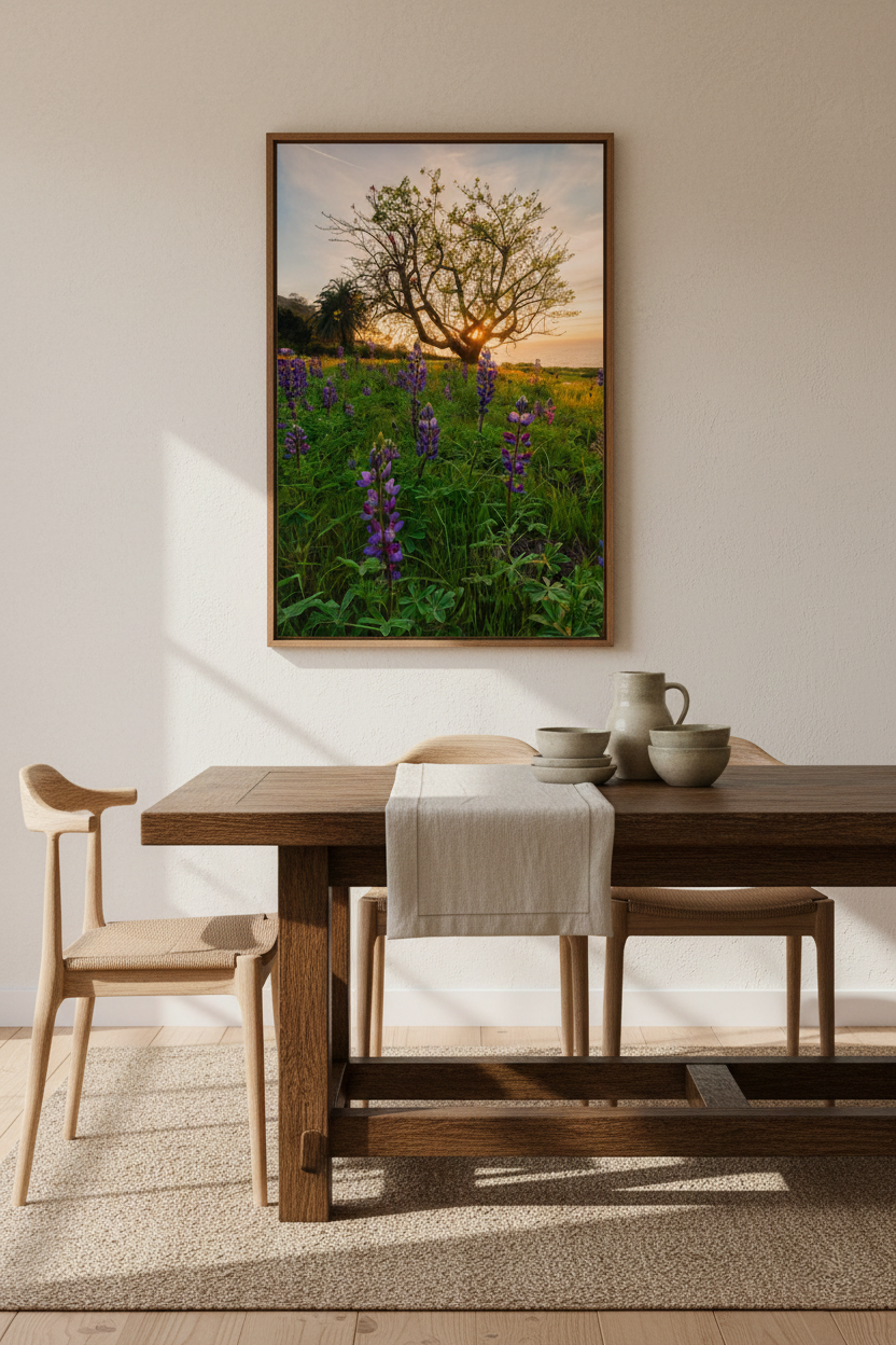Vertical framed lupine wildflowers sunset print hanging on a textured white wall above a rich wooden dining table setup.
