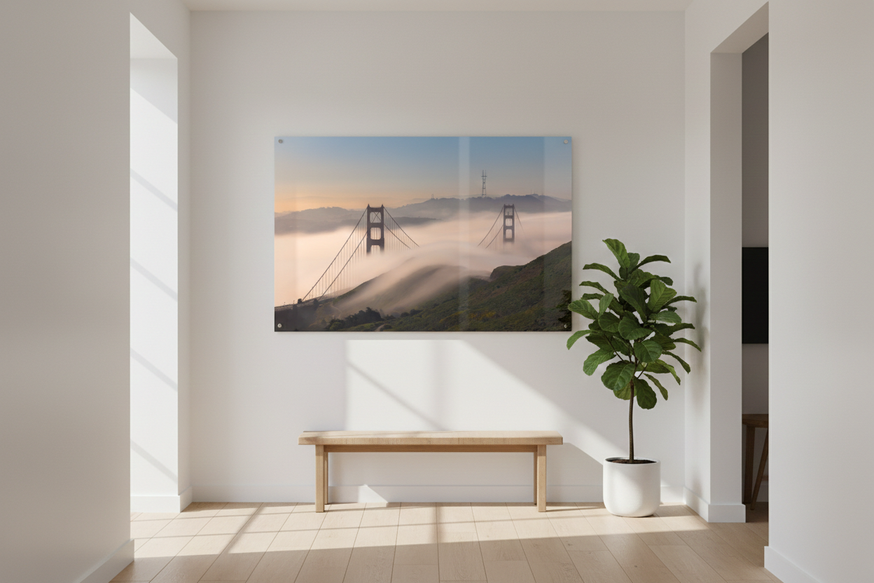 Large acrylic print of the Golden Gate Bridge in low fog mounted above a simple wooden bench in a sunlit entryway.