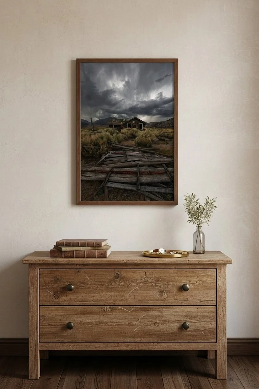Fine art print of an abandoned cabin in the Eastern Sierra in a wooden frame hanging over a rustic wood chest of drawers with decorative books.