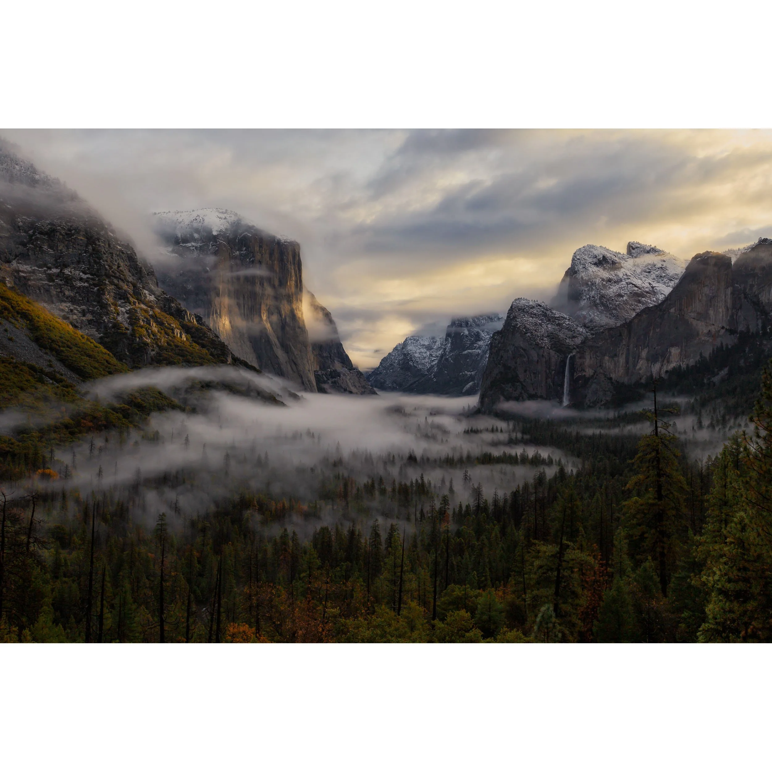 Horizontal fine art landscape photograph of a foggy sunrise at Tunnel View in Yosemite National Park featuring El Capitan, Bridalveil Fall, and snow-dusted peaks.
