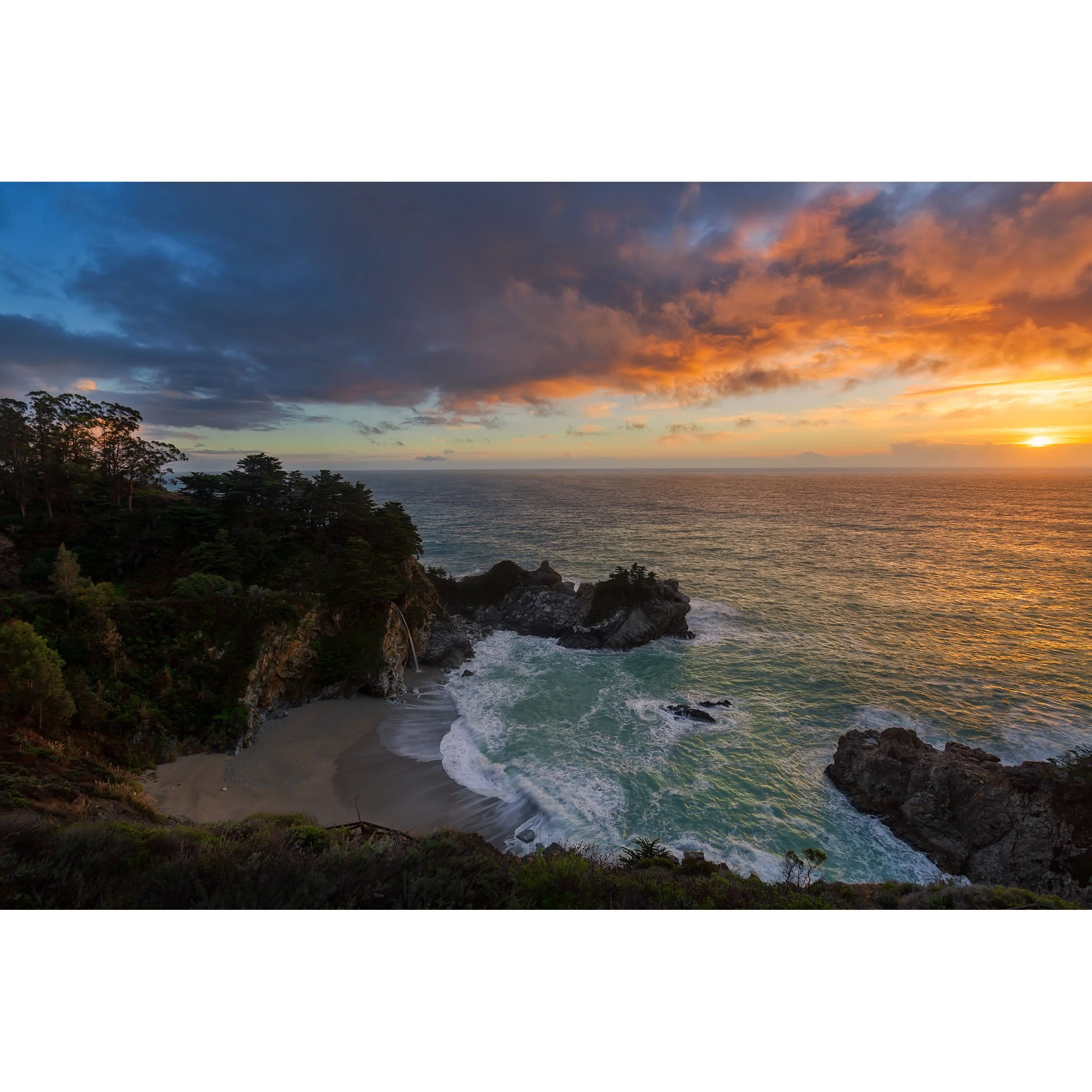 Vibrant fine art landscape photograph of McWay Falls in Big Sur, California, with a turquoise cove, crashing waves, and a dramatic orange, purple, and blue sunset sky.