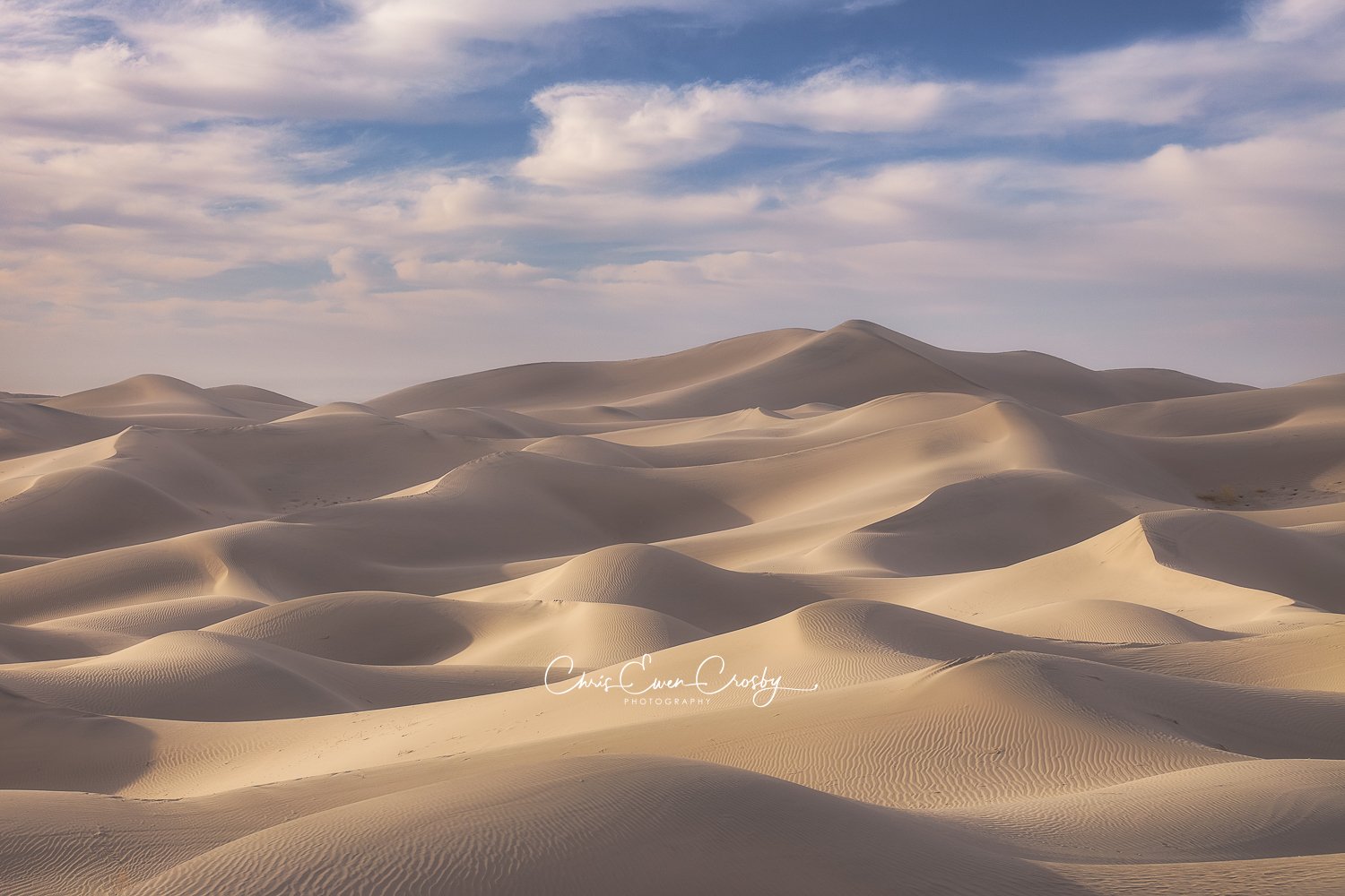 Horizontal minimalist photo of rolling sand dune ridges at Eureka Dunes, Death Valley, in soft morning light.
