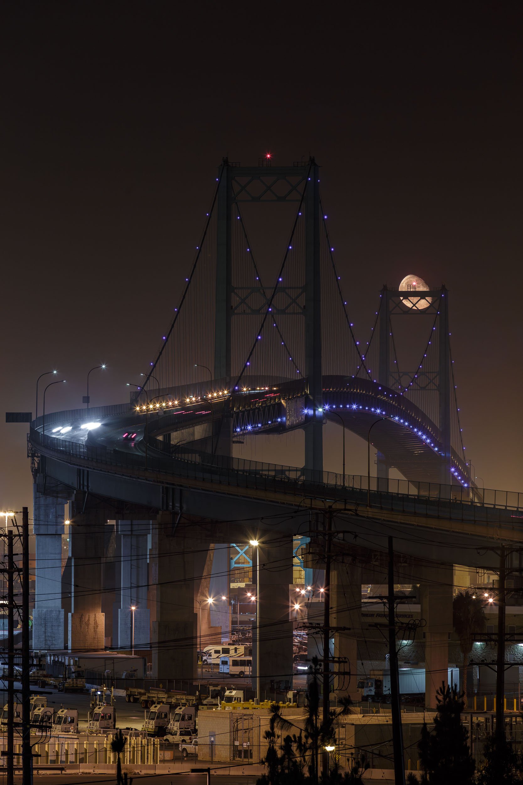 Night long exposure of a full moon framed inside the tower of the Vincent Thomas Bridge in LA.