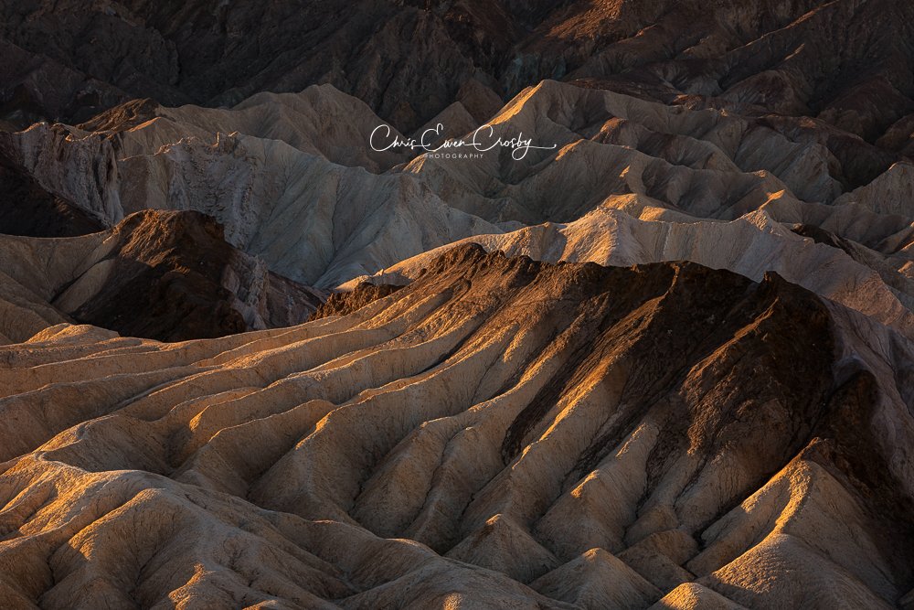 Landscape photo of a sharp, golden mountain ridge shaped like a dragon's spine at sunrise in Death Valley National Park.