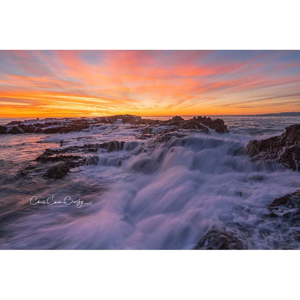 Long exposure ocean photography at sunset in Palos Verdes, California, showing turquoise water rushing over dark coastal rocks under a pink and blue sky.