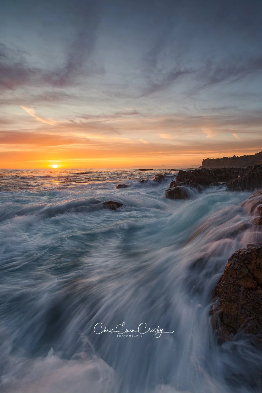Vertical long exposure of ocean water flowing like a waterfall over dark rocks at Palos Verdes Peninsula, California.
