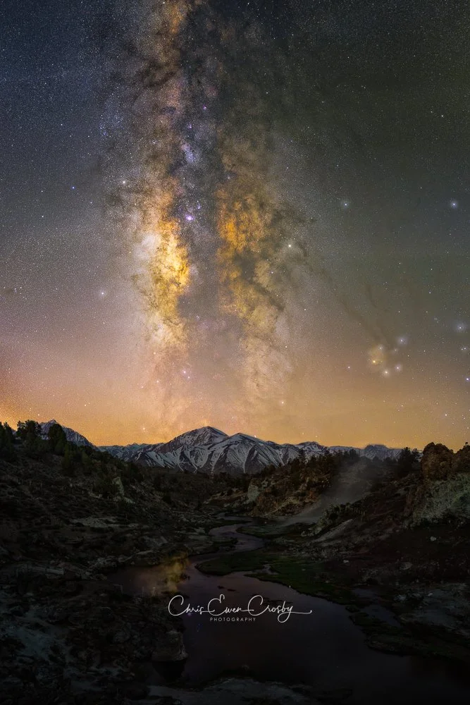 Vertical night photography of the Milky Way galaxy over steaming geothermal water at Hot Creek in Mammoth Lakes, California.