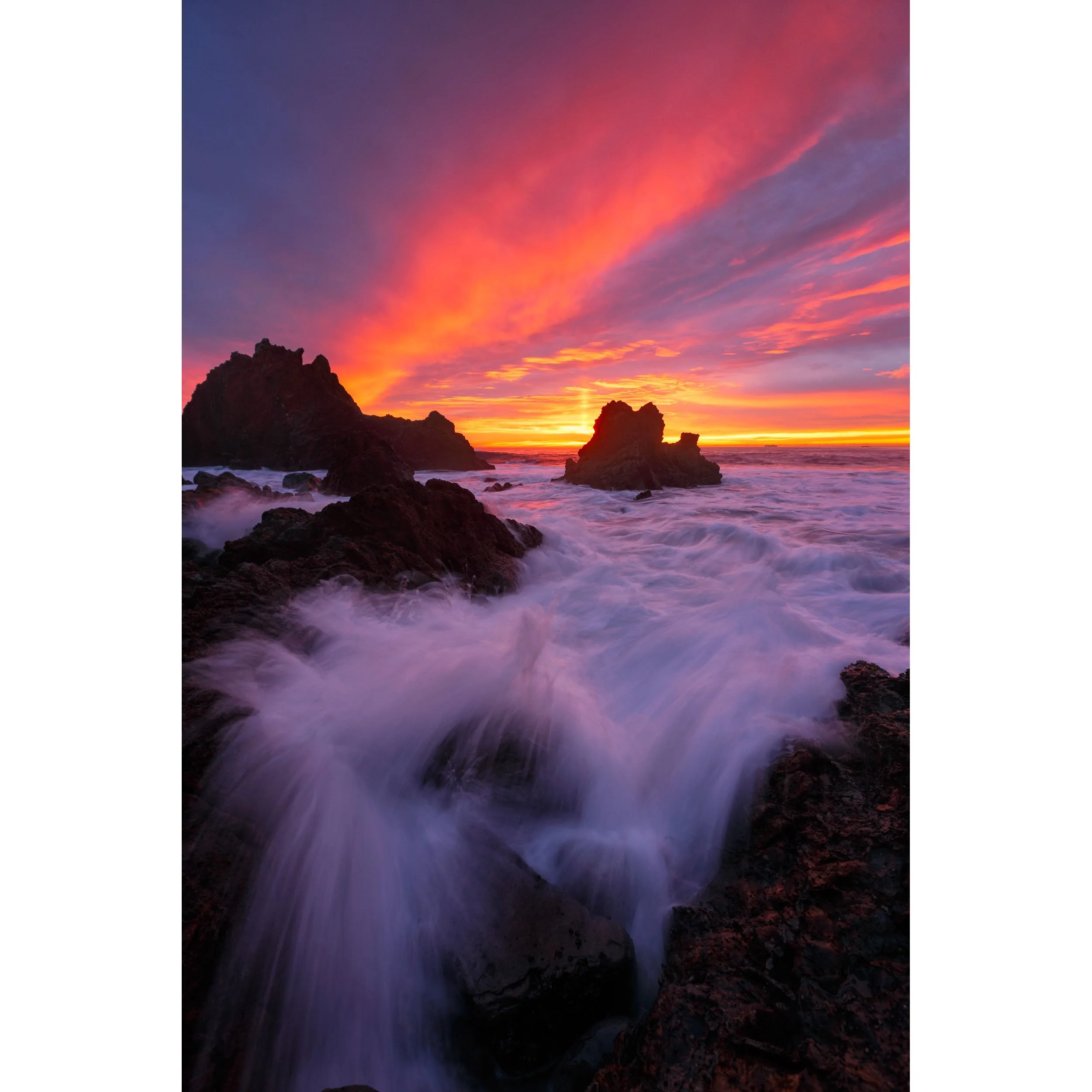 Vertical ocean print of vibrant red and orange sunset over sea stacks on the Palos Verdes coast.