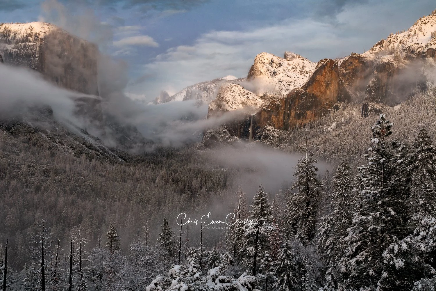 Landscape photo of Yosemite Valley from Tunnel View during a snowy winter sunset with soft pink and blue light.