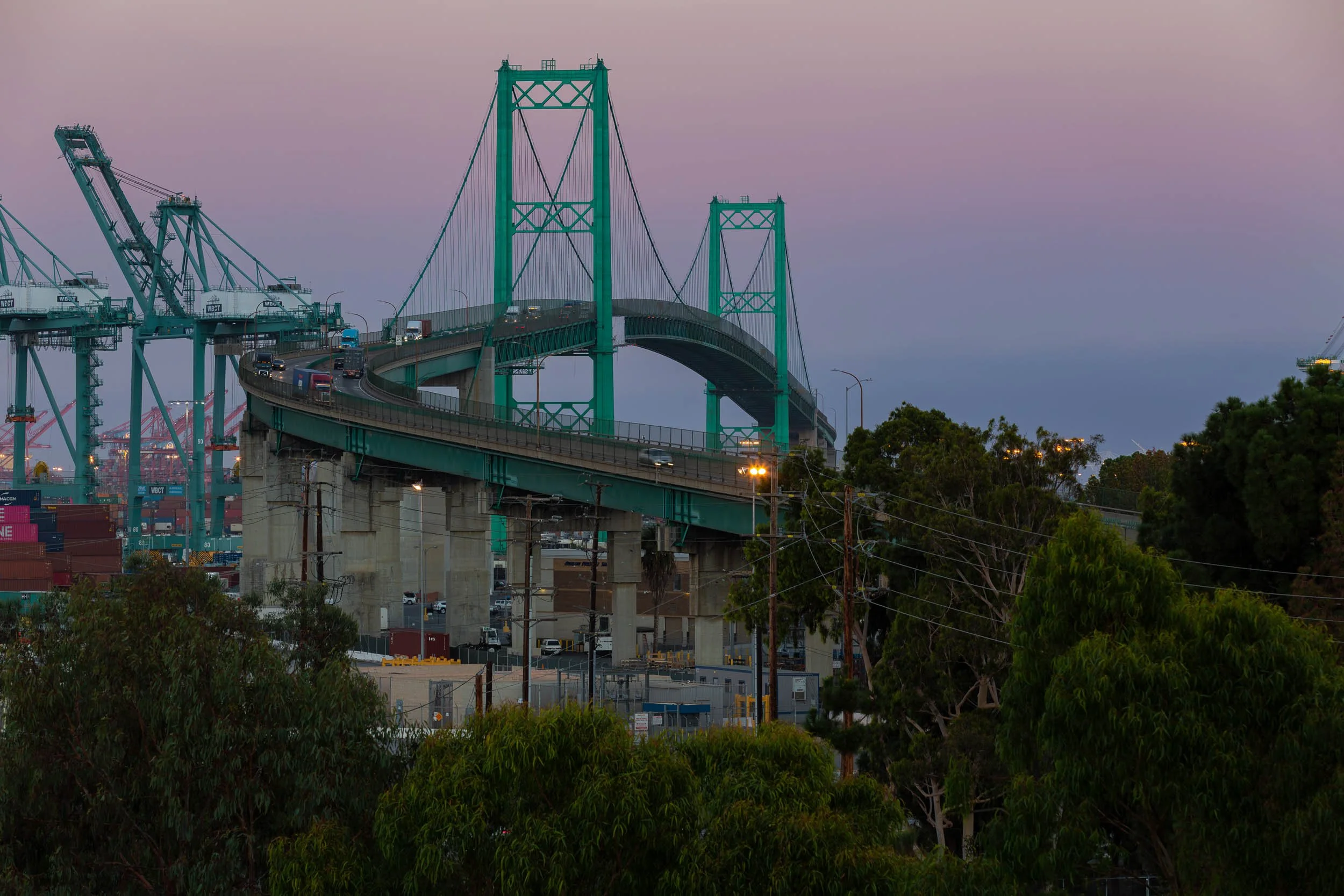 Soft twilight sky over the green Vincent Thomas Bridge structure and harbor cranes.