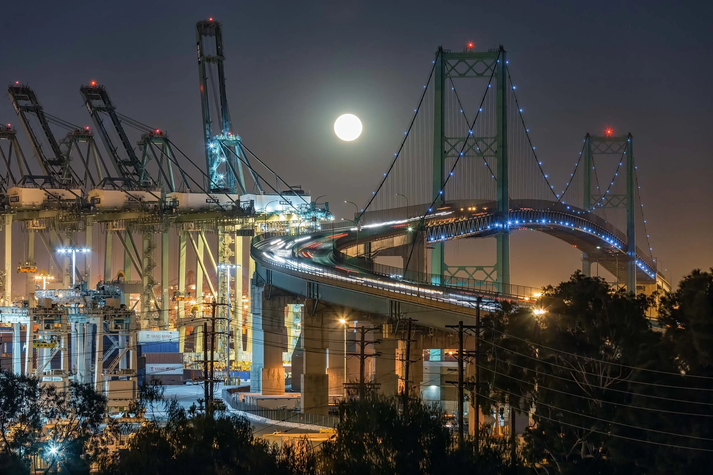 Full moon over the Vincent Thomas Bridge and lit harbor cranes during a night photography class.