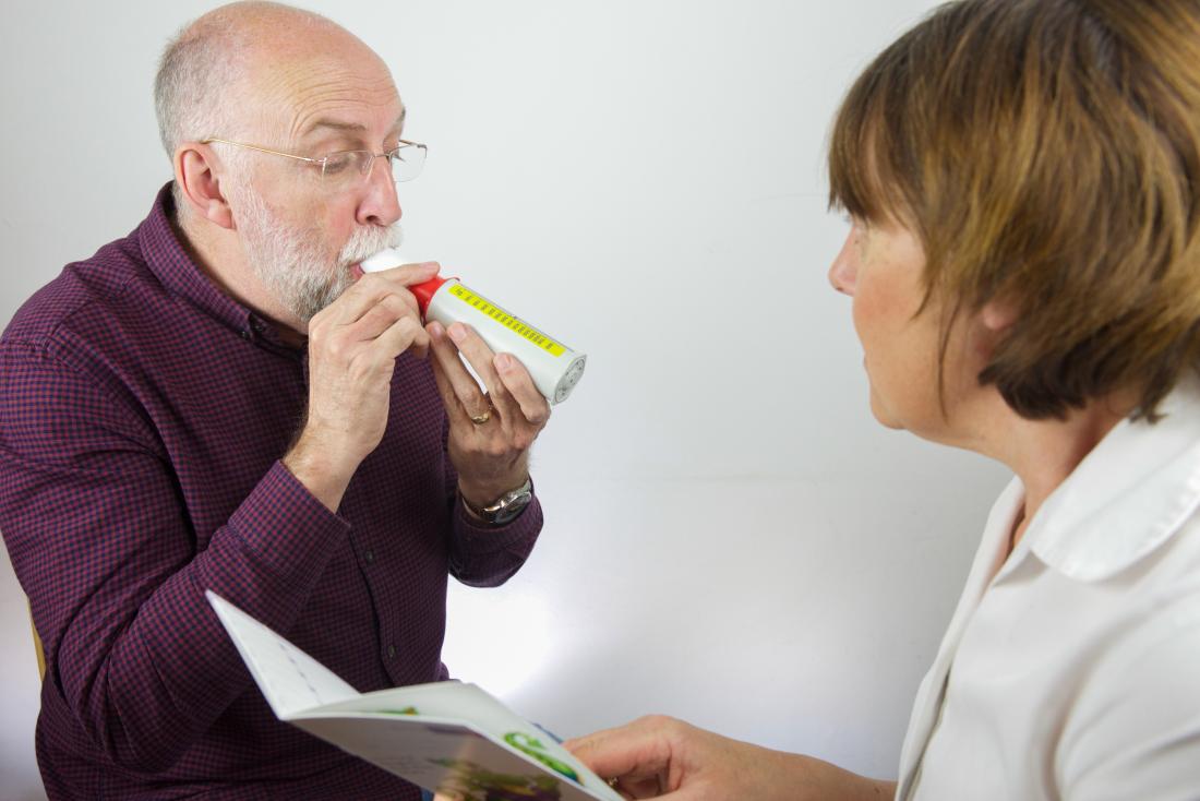 man-breathing-into-peak-flow-meter-to-test-lung-capacity-as-part-of-pulmonary-function-tests.jpg